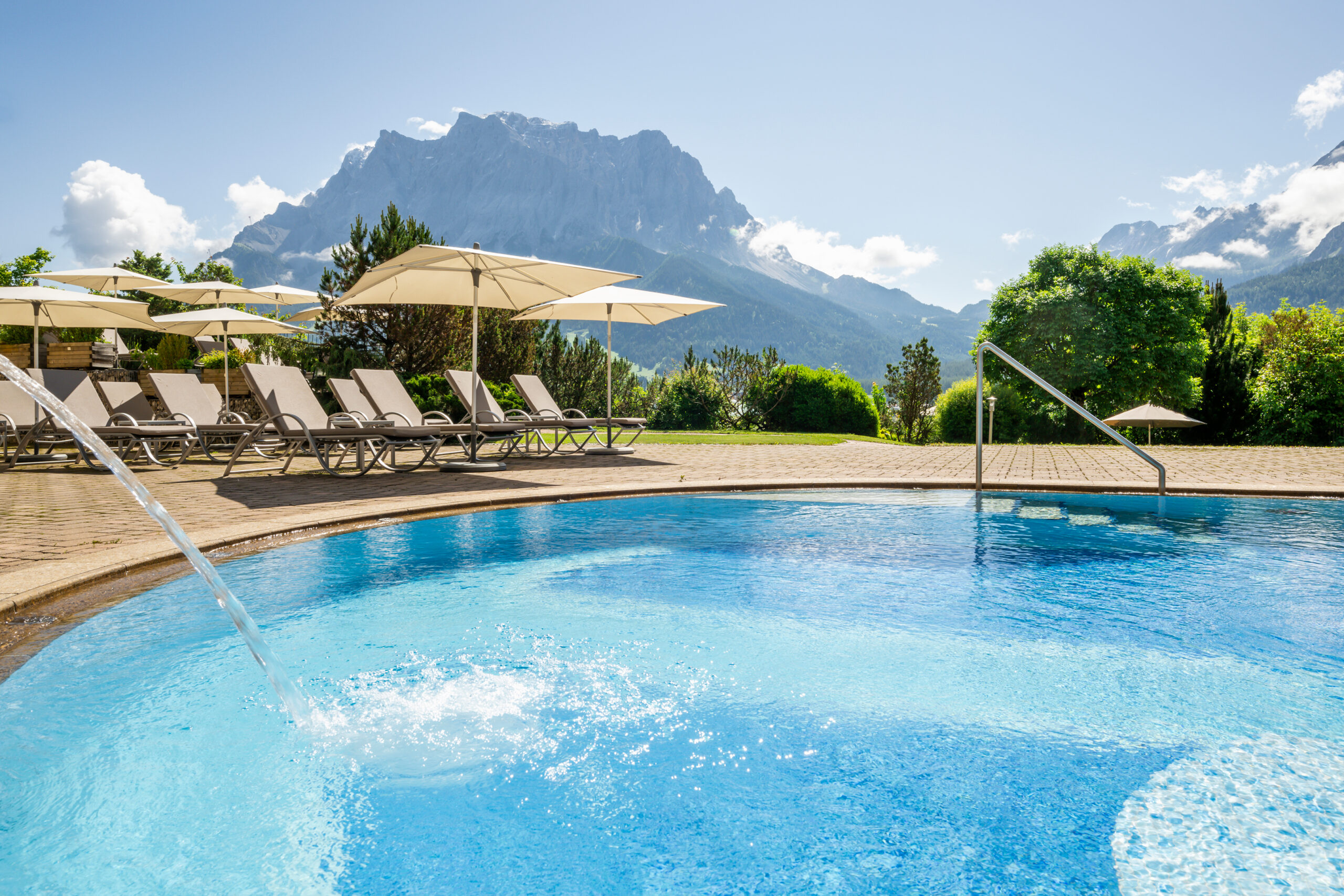 Pool mit Liegestühlen und weißen Sonnenschirmen