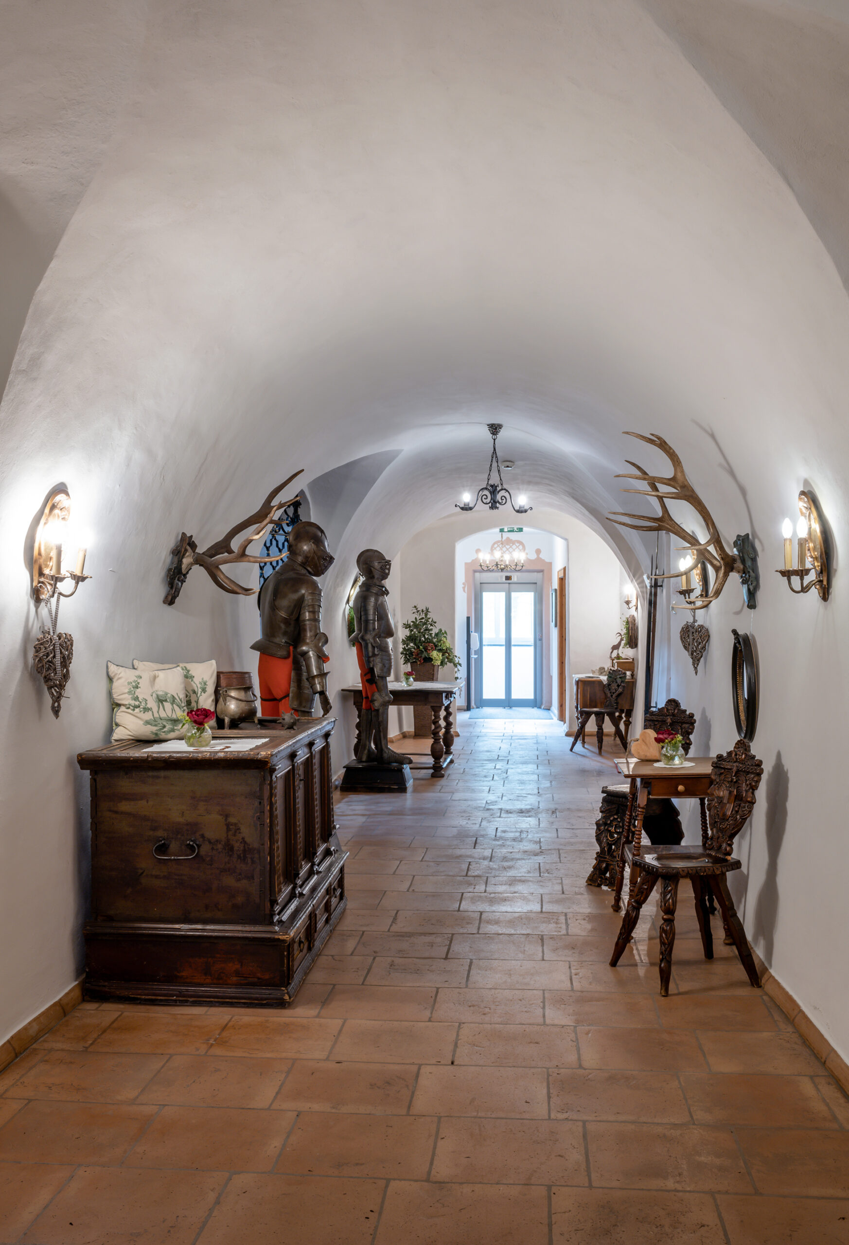 Gang mit Ritterrüstungen und Geweihen an der Wand