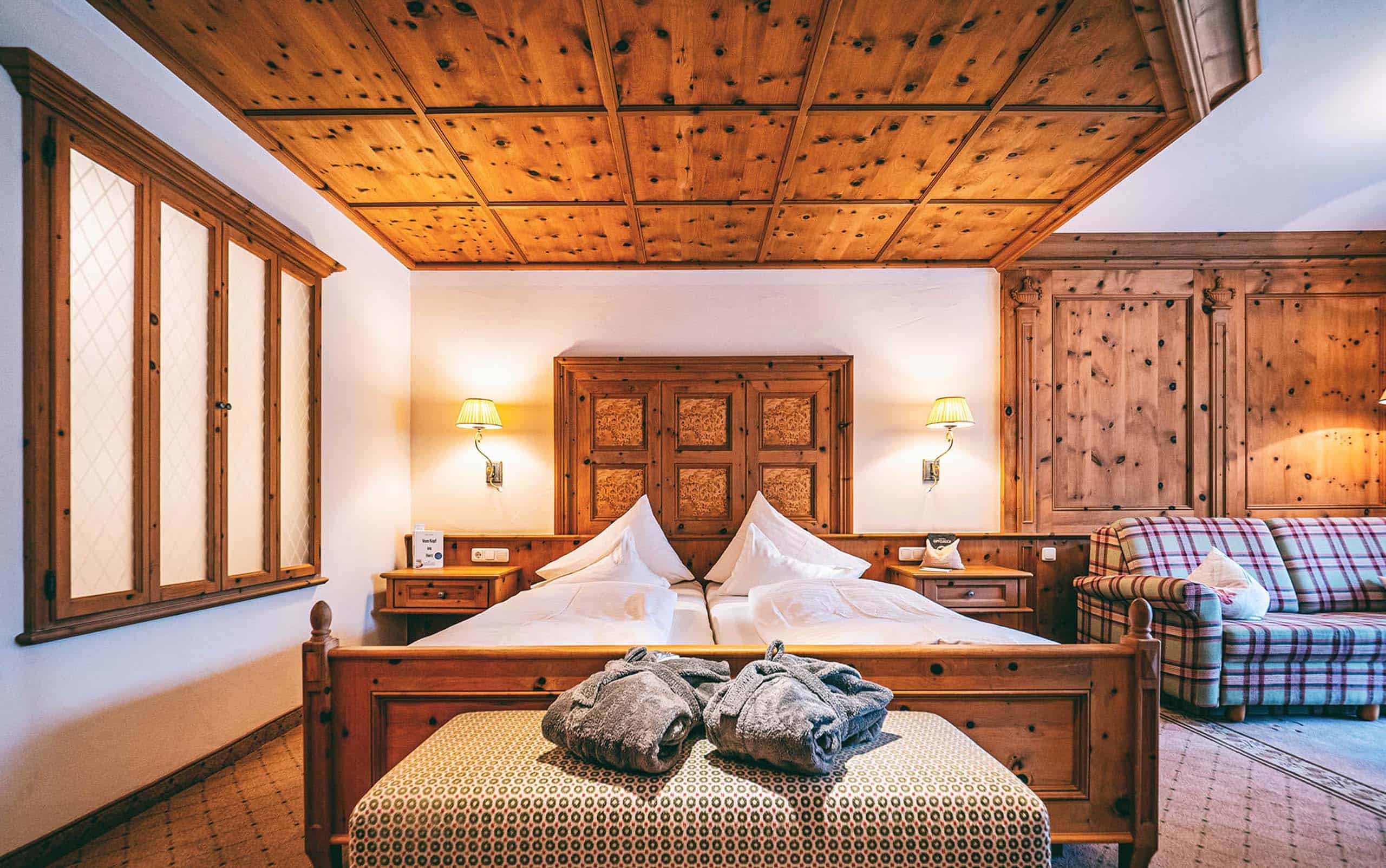 JuniorSuiteBGrubig2 Zimmer mit viel Holzelementen, Doppelbett und zwei Bademänteln