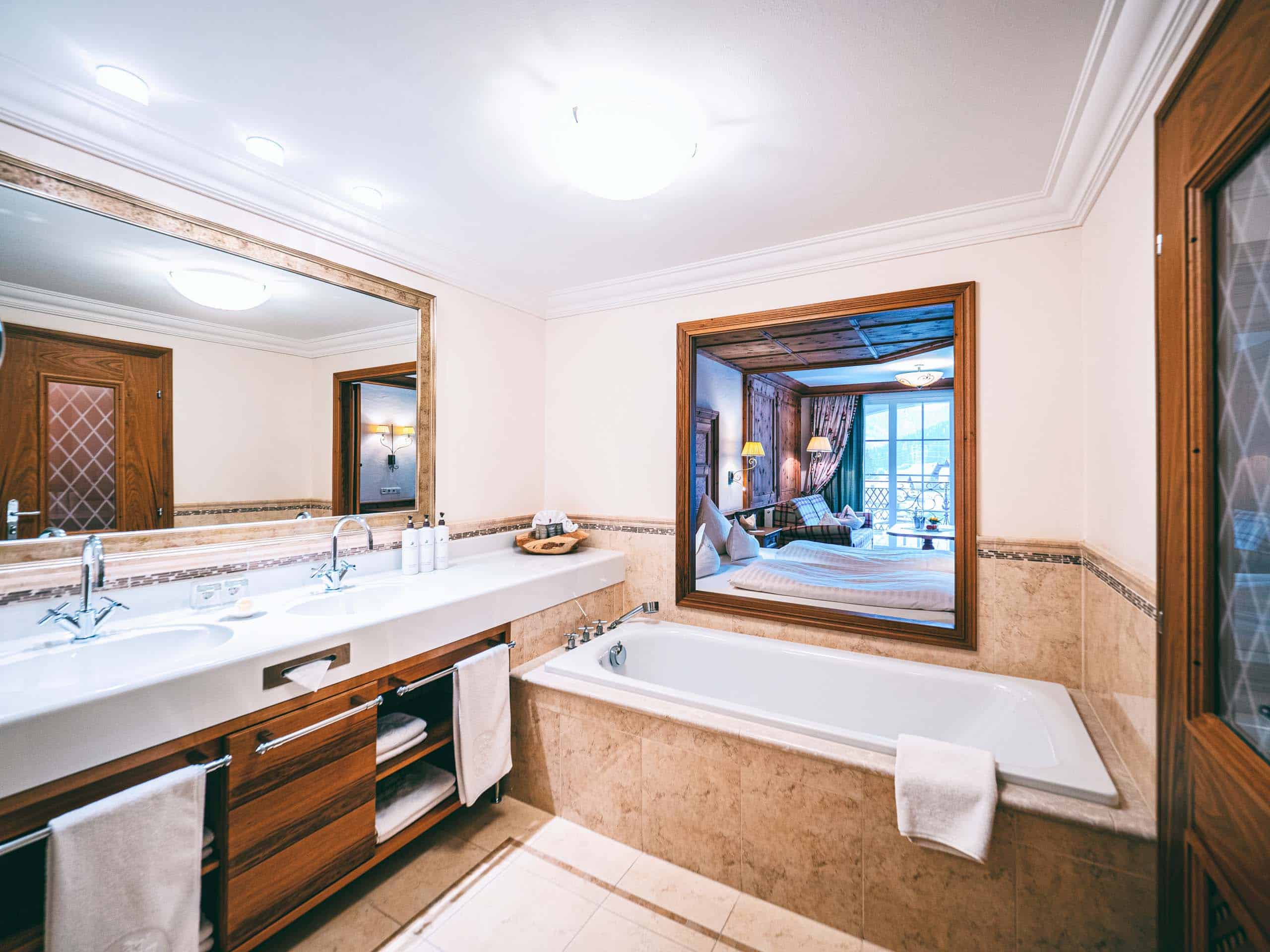 JuniorSuiteBGrubig3 Badezimmer mit Doppelwaschbecken und Badewanne mit Blick zum Schlafzimmer