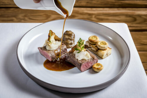 Fleischgericht wird mit Sauce übergossen - Hotel Post 4*S
