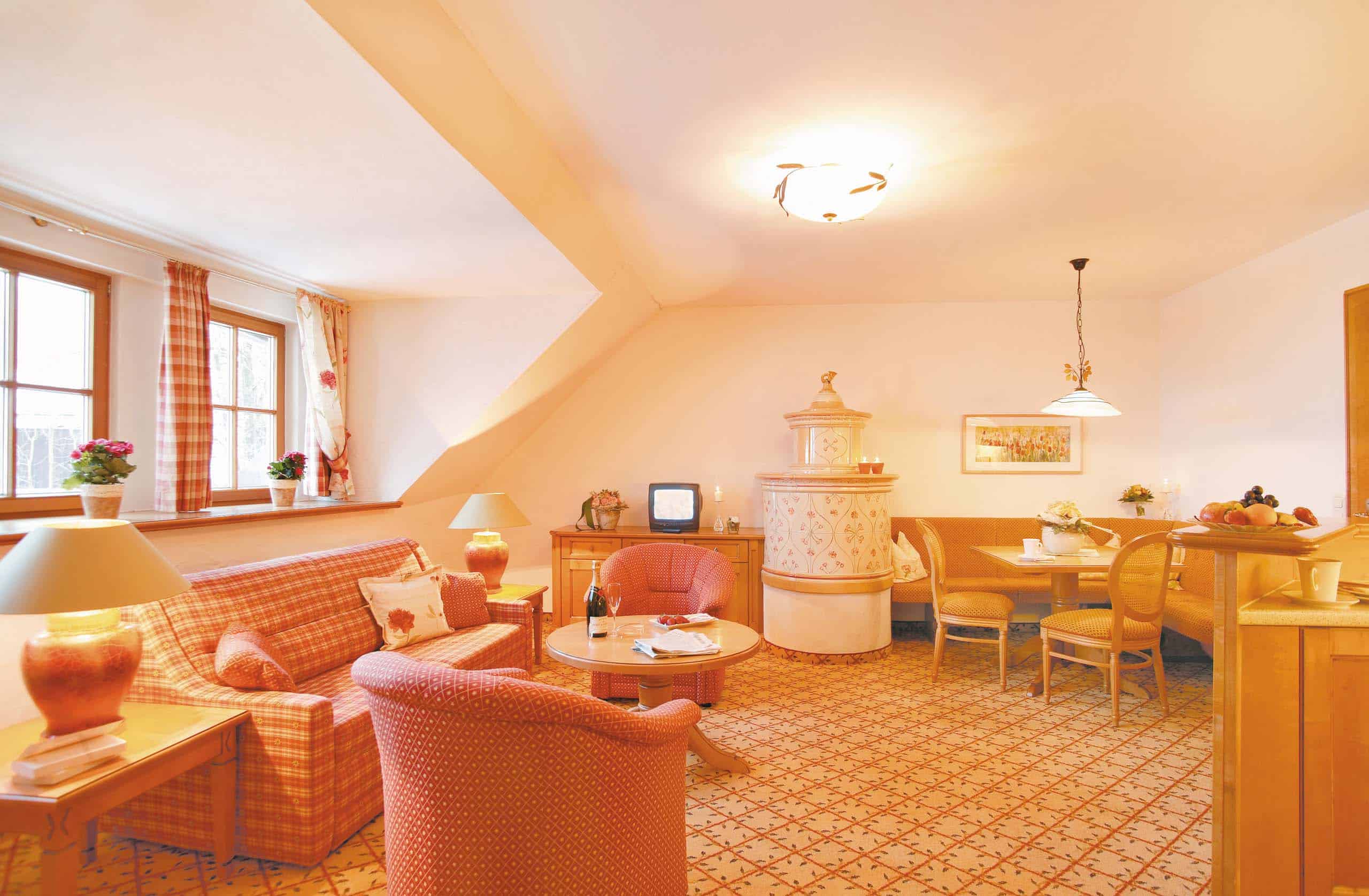 FamilySuitedeLuxeFdLPostschlössl1 großes Zimmer mit Sofa, Sesseln, Kachelofen und Eckbank