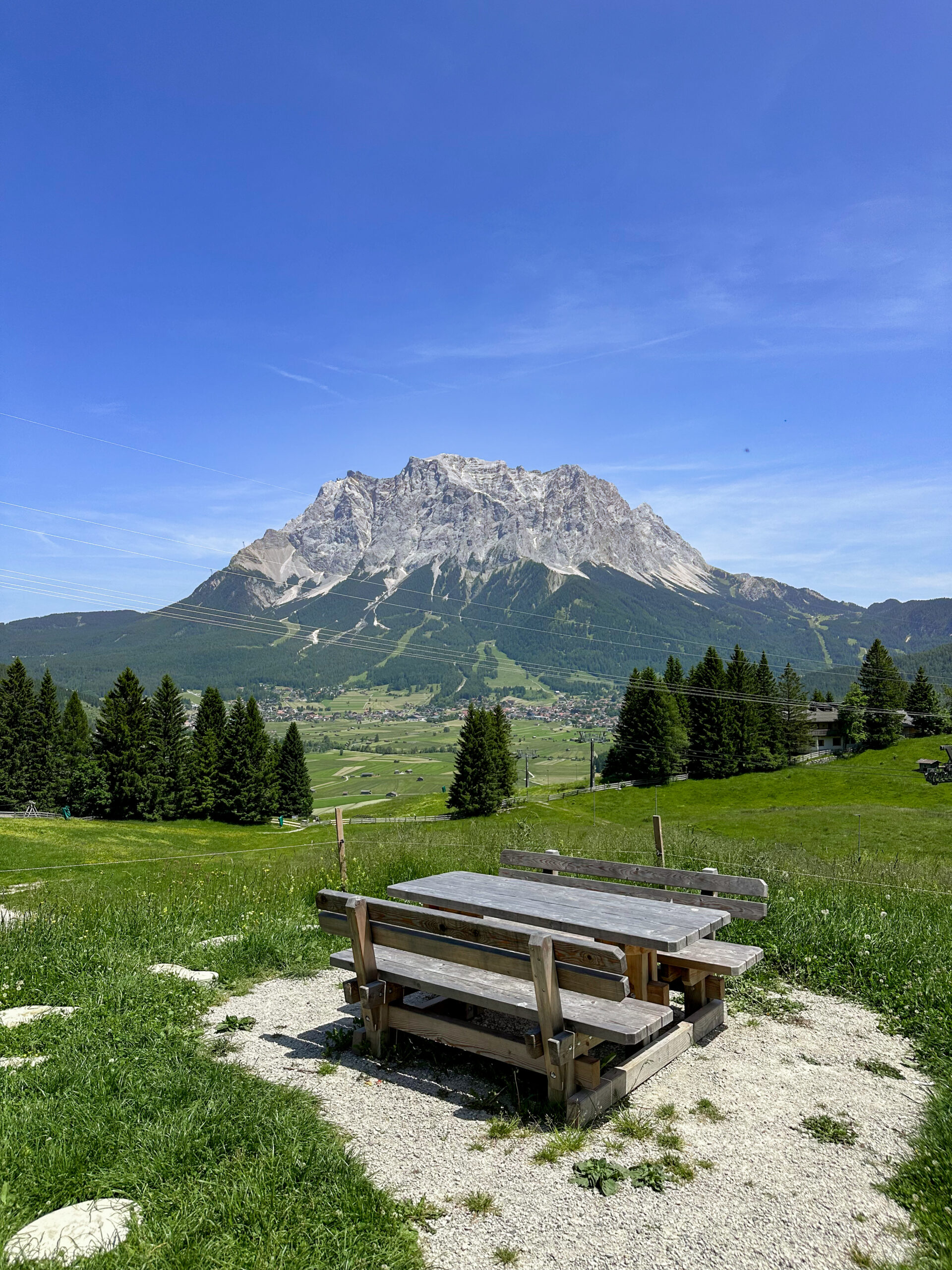 Holztisch mit zwei Holzbänken mitten in Wiese vor Berg